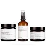 Fire hudplejeprodukter mærket "Evolve Daily Skin Essentials Trio" inklusive en rensende smelte, fugtmist, ansigtscreme og omega-serum, arrangeret på en hvid baggrund.