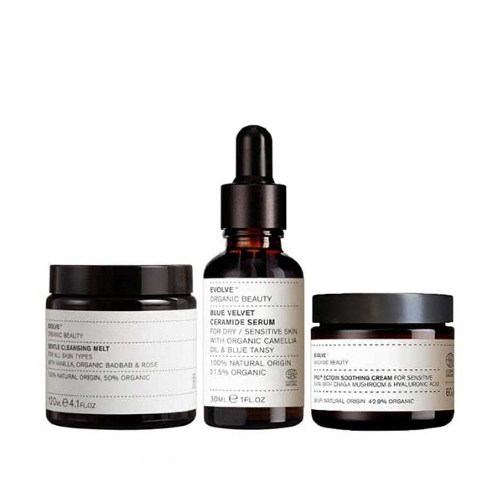 Tre kosmetiske produkter fra Evolve Beauty: et serum, en rensende smelte og en ansigtscreme fra Evolve's beroligende hudbundt, arrangeret på en hvid baggrund.