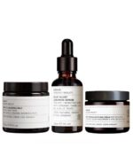 Tre kosmetiske produkter fra Evolve Beauty: et serum, en rensende smelte og en ansigtscreme fra Evolve's beroligende hudbundt, arrangeret på en hvid baggrund.