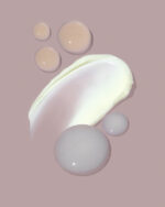 En beige baggrund med udtværinger og dråber af forskellige hudplejeprodukter, inklusive creme- og gelteksturer, viser den luksuriøse Glo SkinBeauty Restorative Cream 50 ml.
