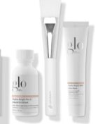 Three Glo Skin Beauty Radiant Spa Day Kit - Begrænsede hudplejeprodukter: en hvid flaske Hydra-Bright Pro 5 Liquid Exfoliant, en hvid tube Hydra-Bright AHA Glow Mask og en hvid påføringsbørste.