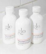 Tre hvide flasker mærket "Glo Hydra-Bright Pro 5 Liquid Exfoliant 60 ml" vist på en hvid overflade.